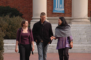 A faculty member and two students walking on campus